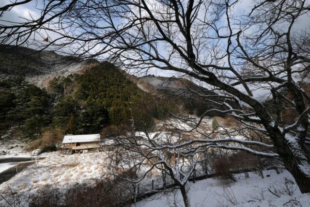 View looking down at the village of Nagoro across a river, covered in snow.